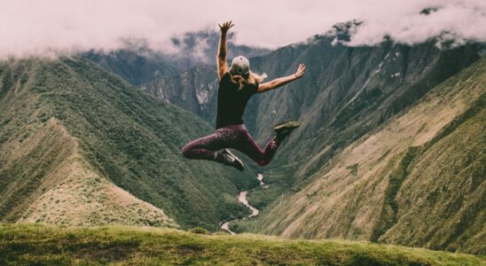 woman jumping on green mountains